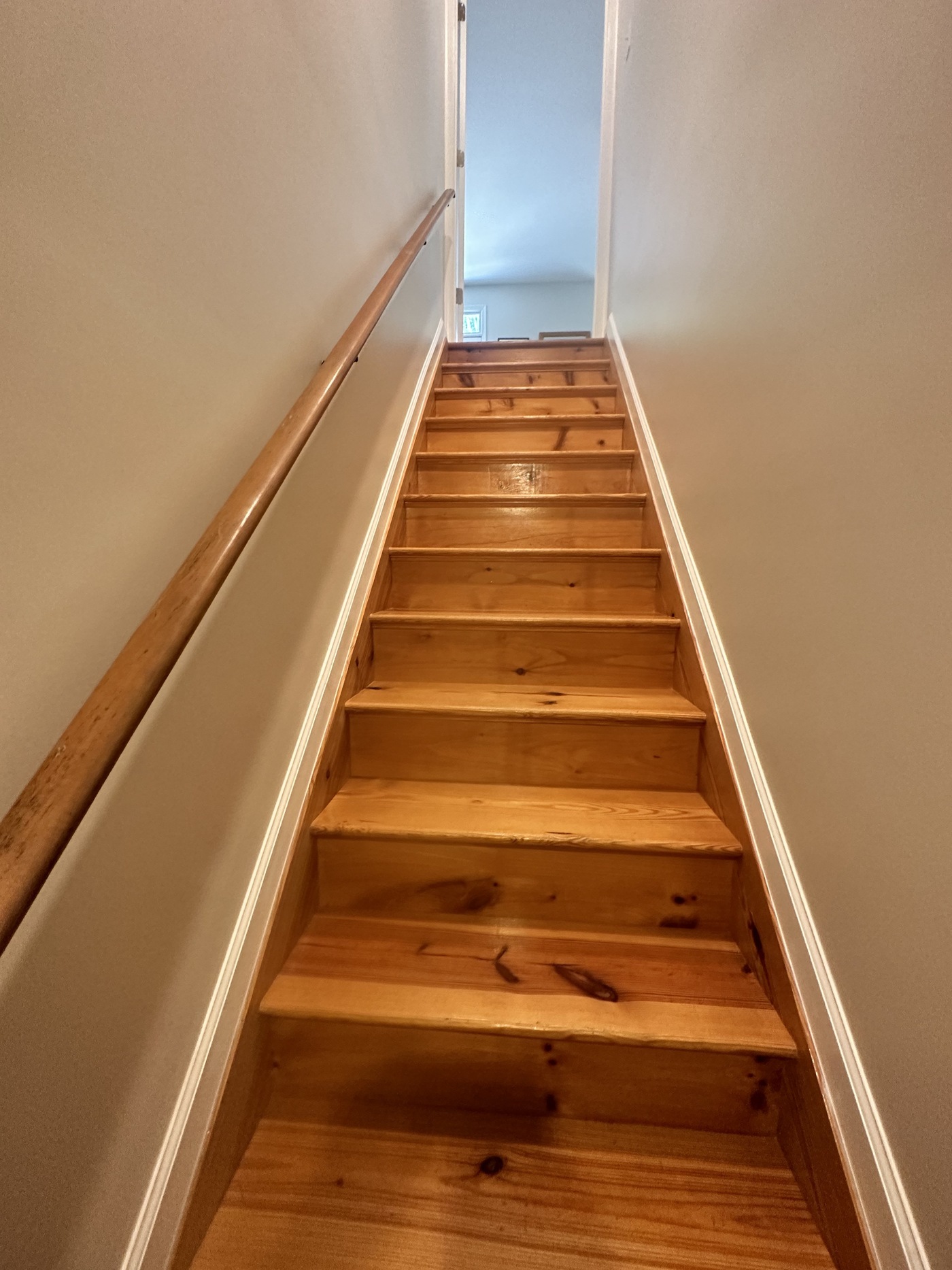 Finished knotty pine staircase with a wood handrail in a Charlottesville-area home
