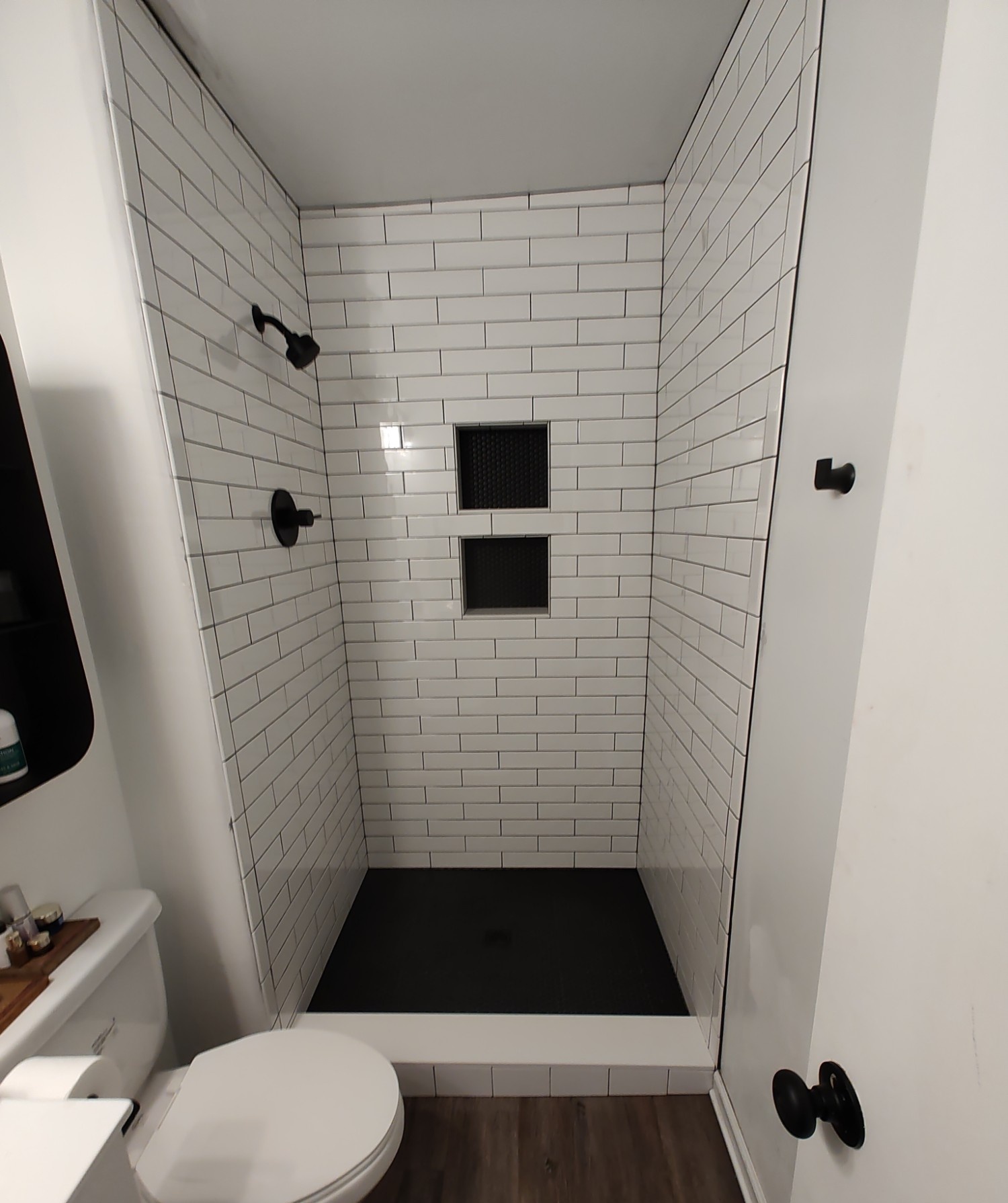 Finished white subway tile shower with black hex floor
