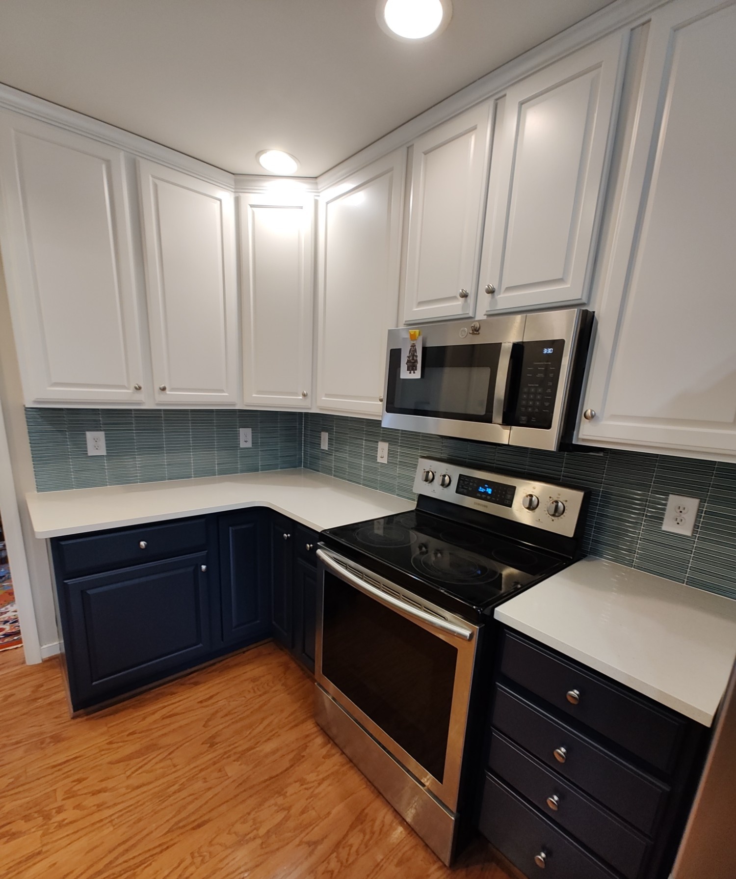 Kitchen with white and navy cabinets, teal tile backsplash
