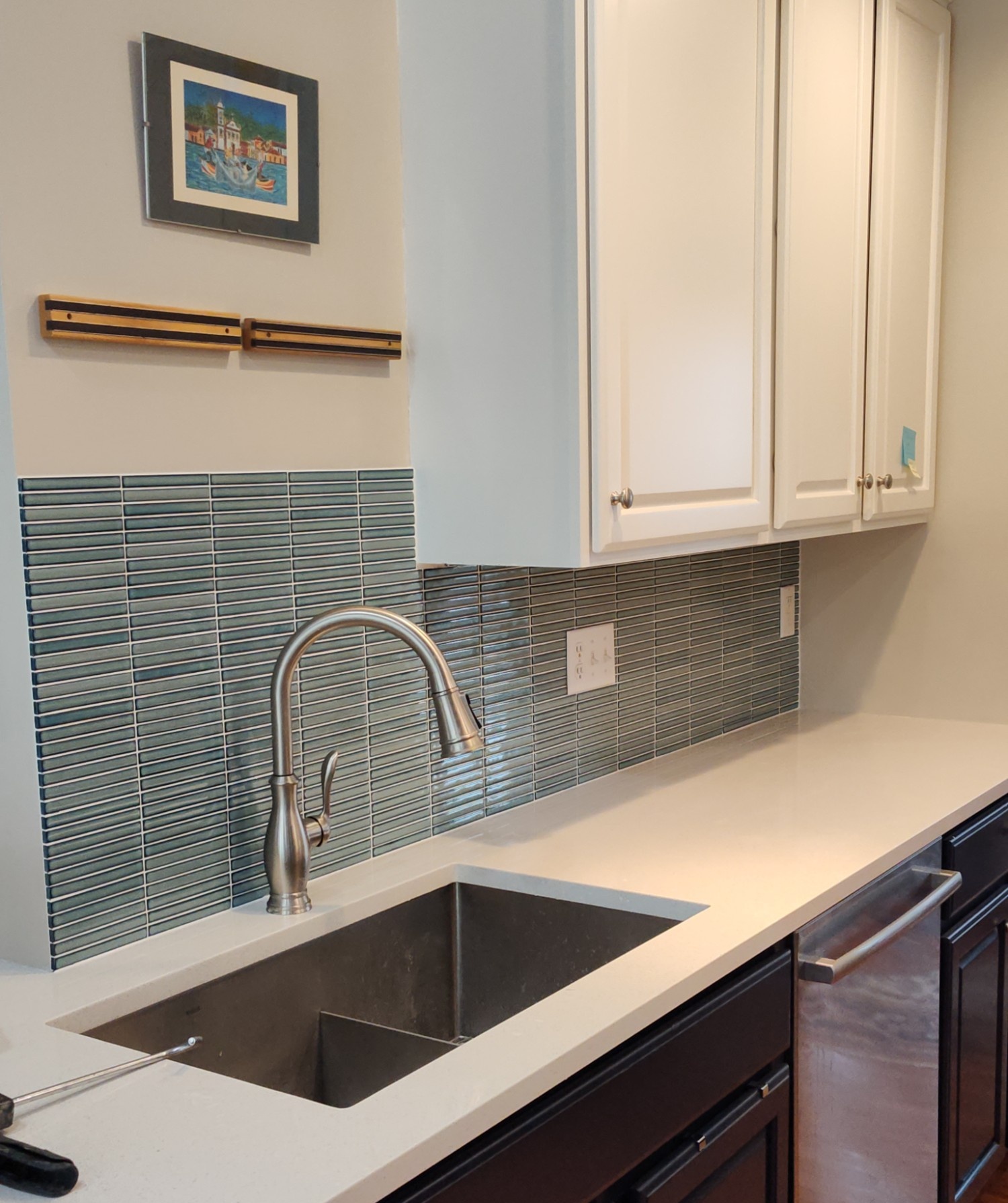 Kitchen sink with teal glass tile backsplash and quartz counters