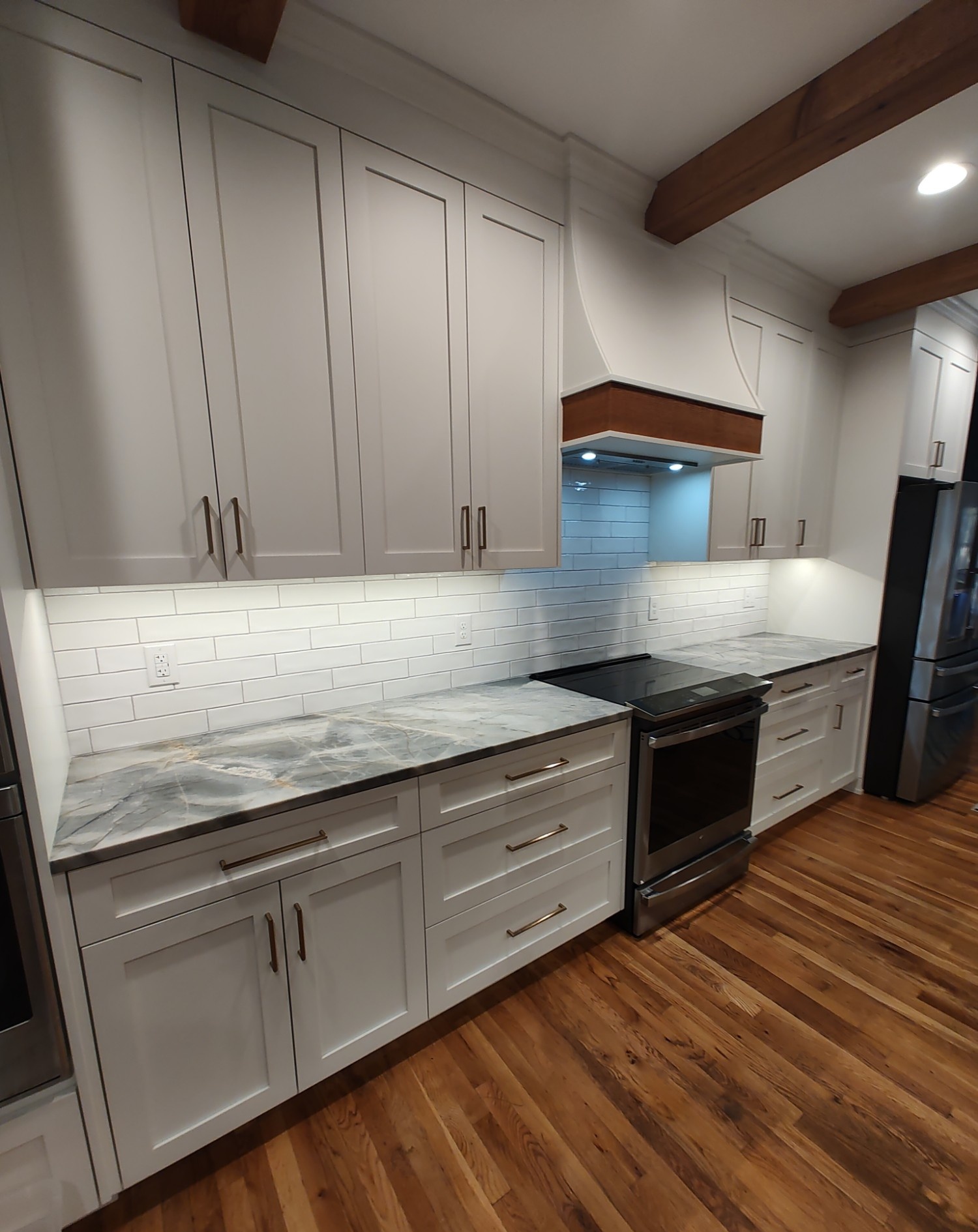 Wide kitchen view with wood ceiling beams and range hood
