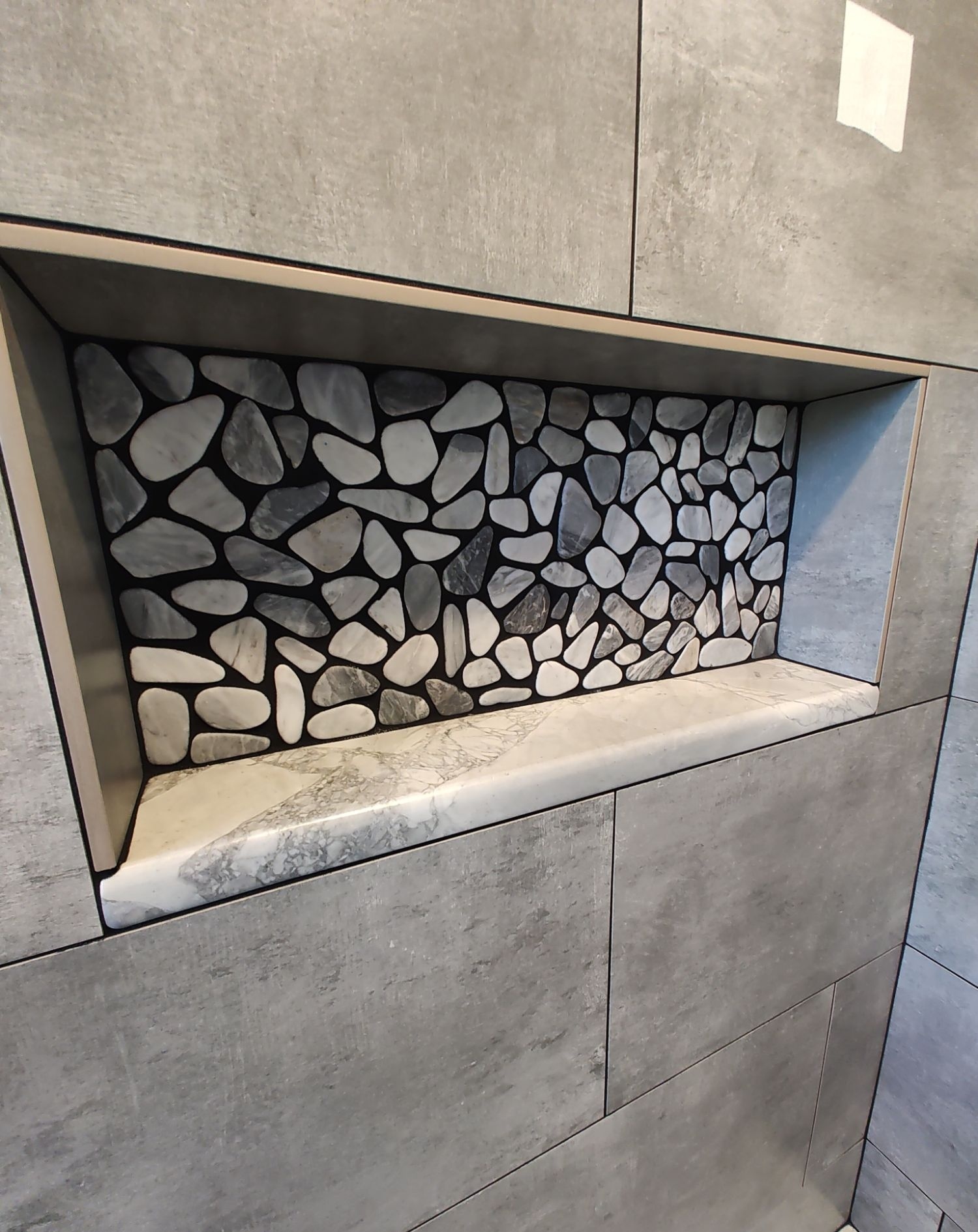 River pebble tile niche with marble ledge