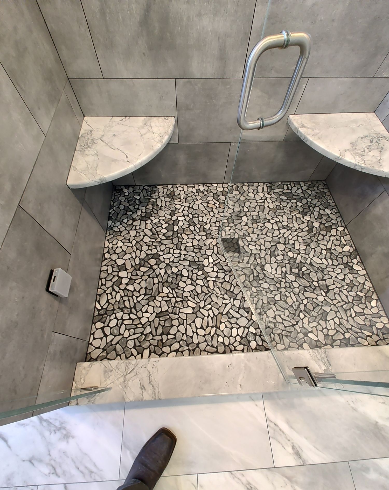 River pebble shower floor with grab bar, top-down view