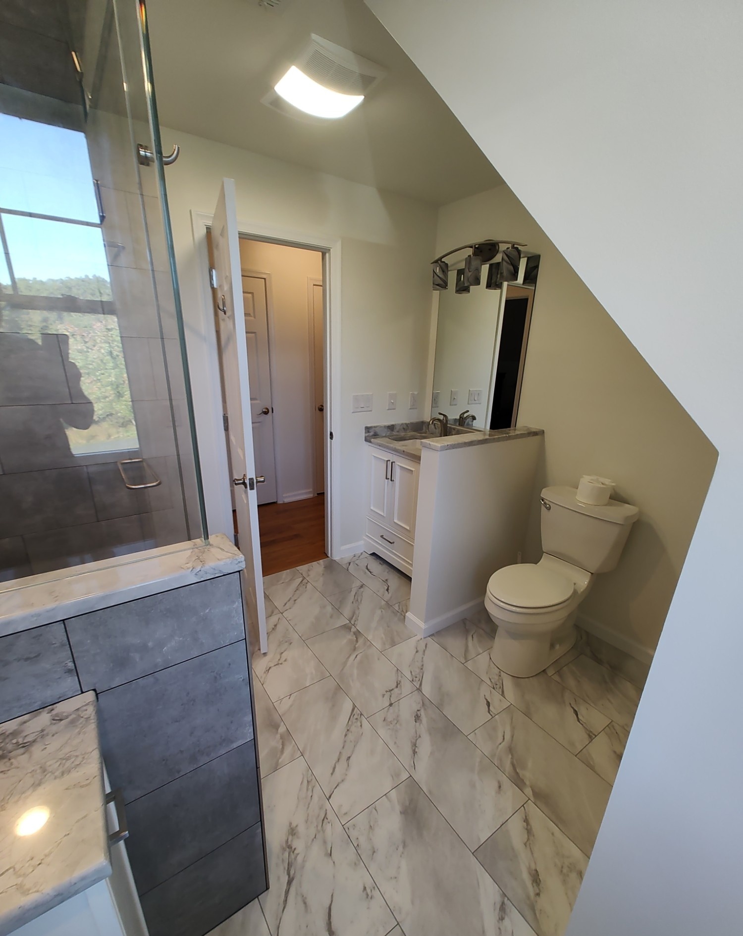 Bathroom hallway with vanity, mirror, and toilet