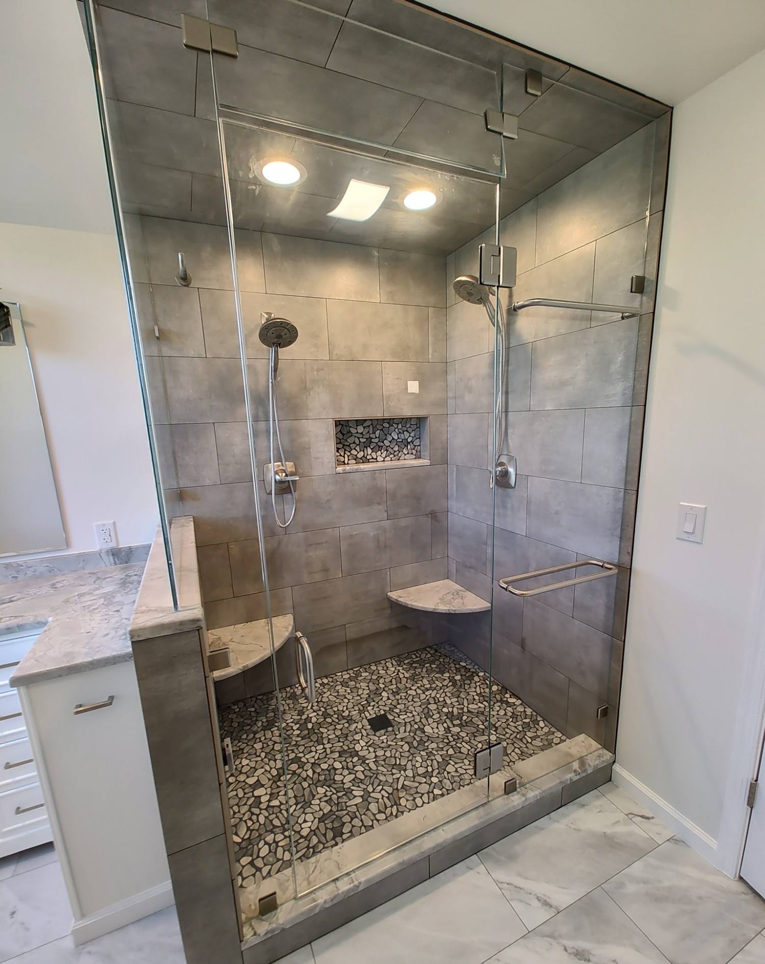Walk-in shower with dual shower heads and marble corner seats