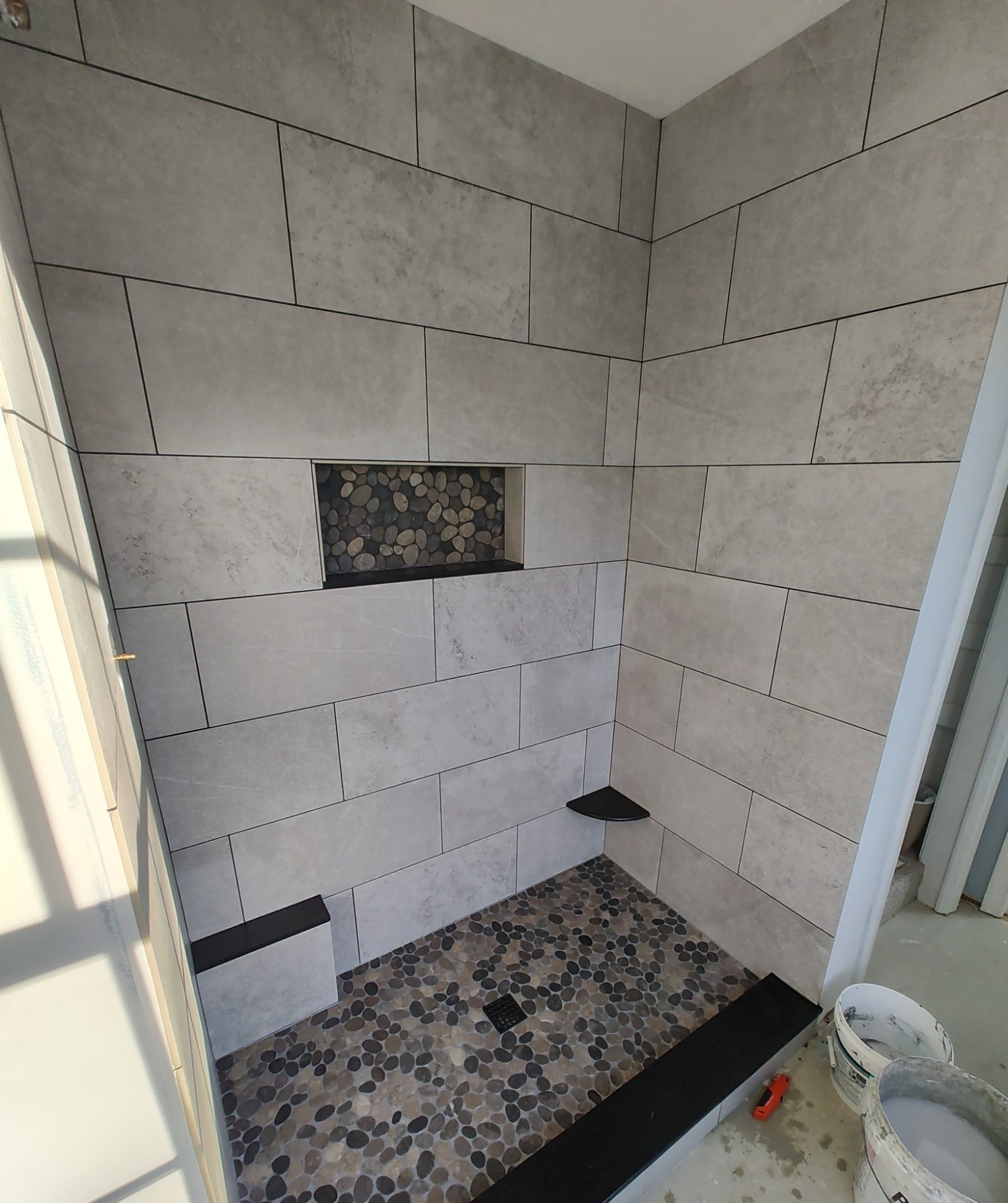 Pebble tile shower floor installation in progress