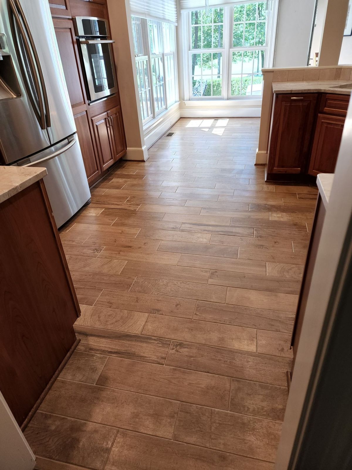 Wood-look plank tile flooring through a hallway to a sunroom