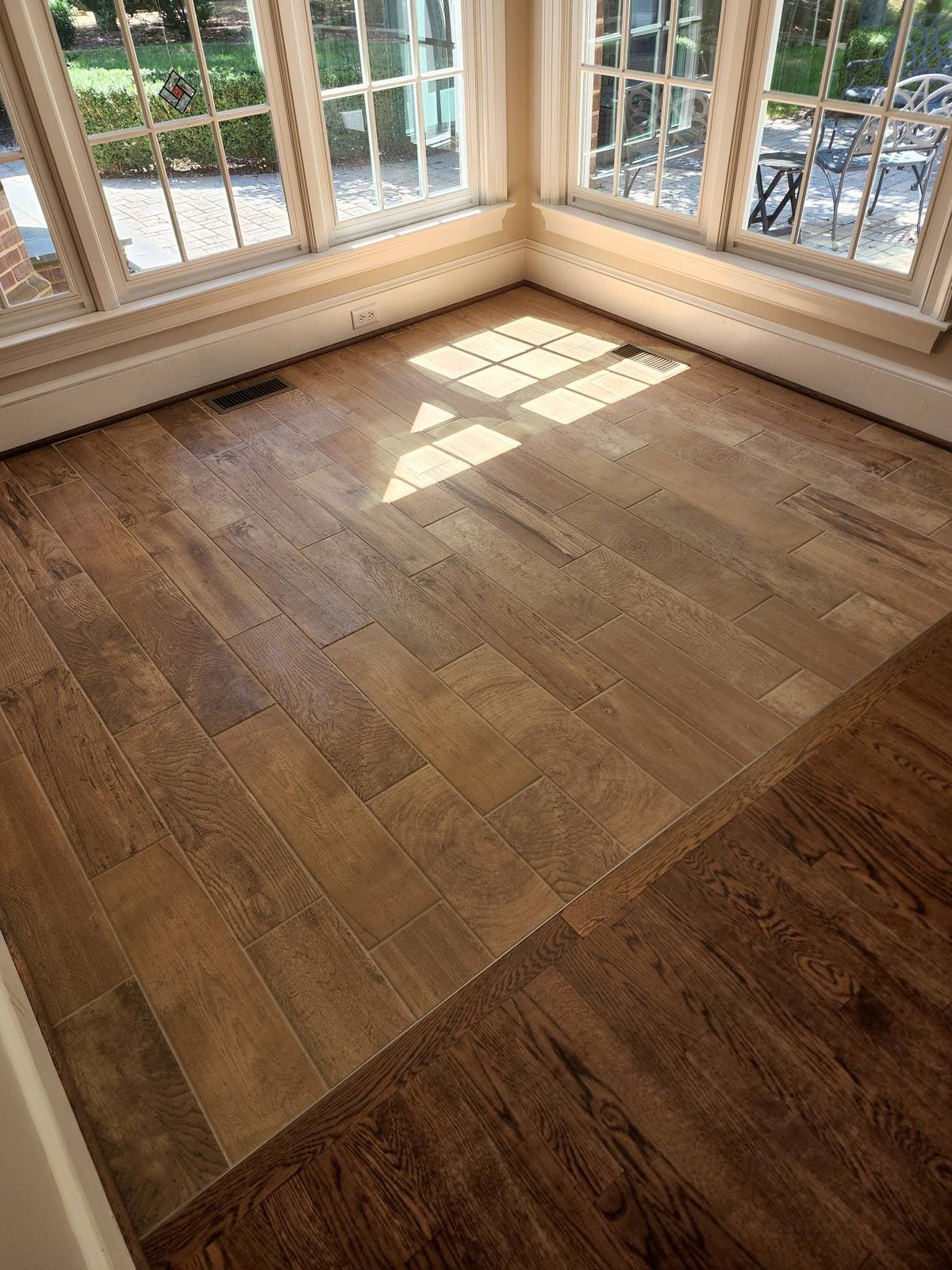 Wood-look plank tile flooring in a sunroom with large windows