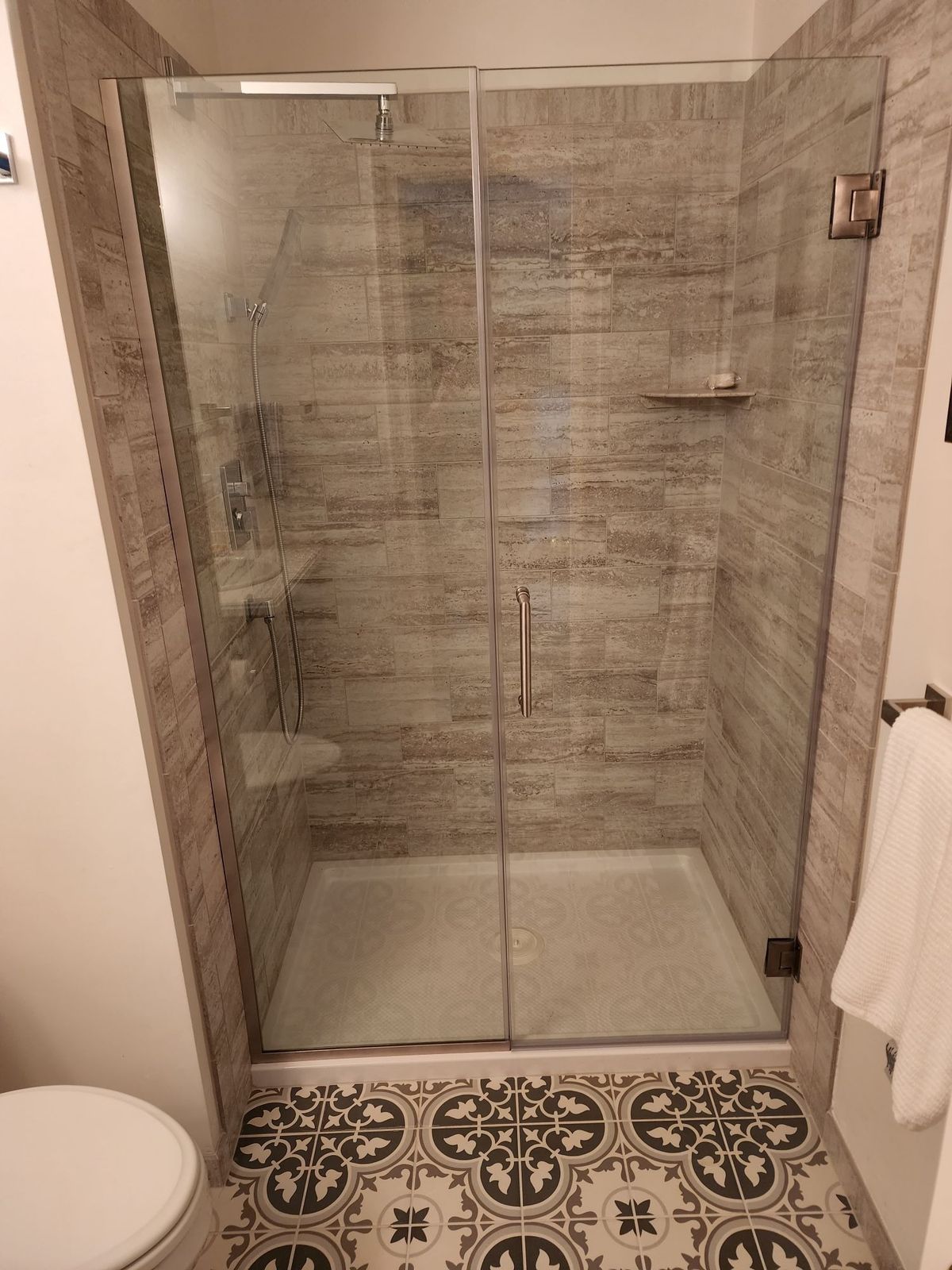 Frameless glass shower with travertine tile and rain shower head