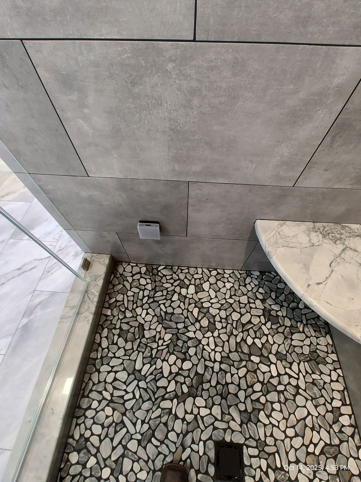 River pebble tile shower floor with drain and marble counter edge