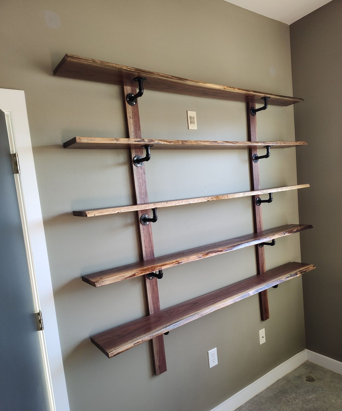 Live-edge walnut floating shelves on black pipe brackets
