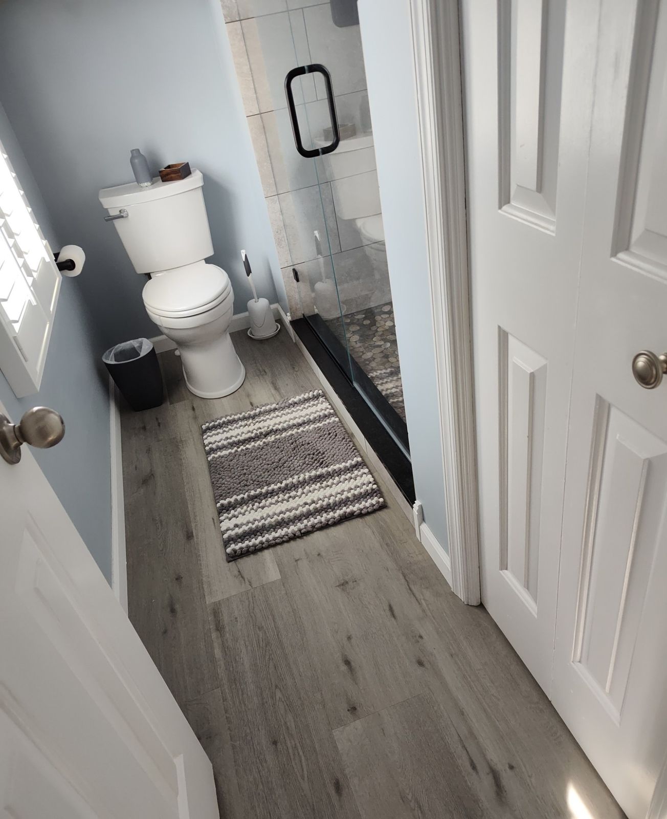 Finished bathroom with glass shower door, tile floor, and bath mat