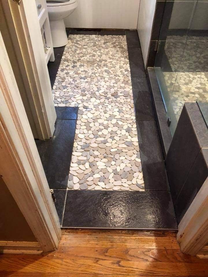 Bathroom hallway view with river pebble tile runner and glass shower door