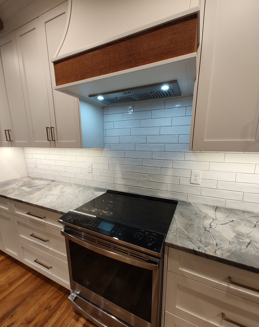 Custom range hood with a wood accent panel over the cooktop