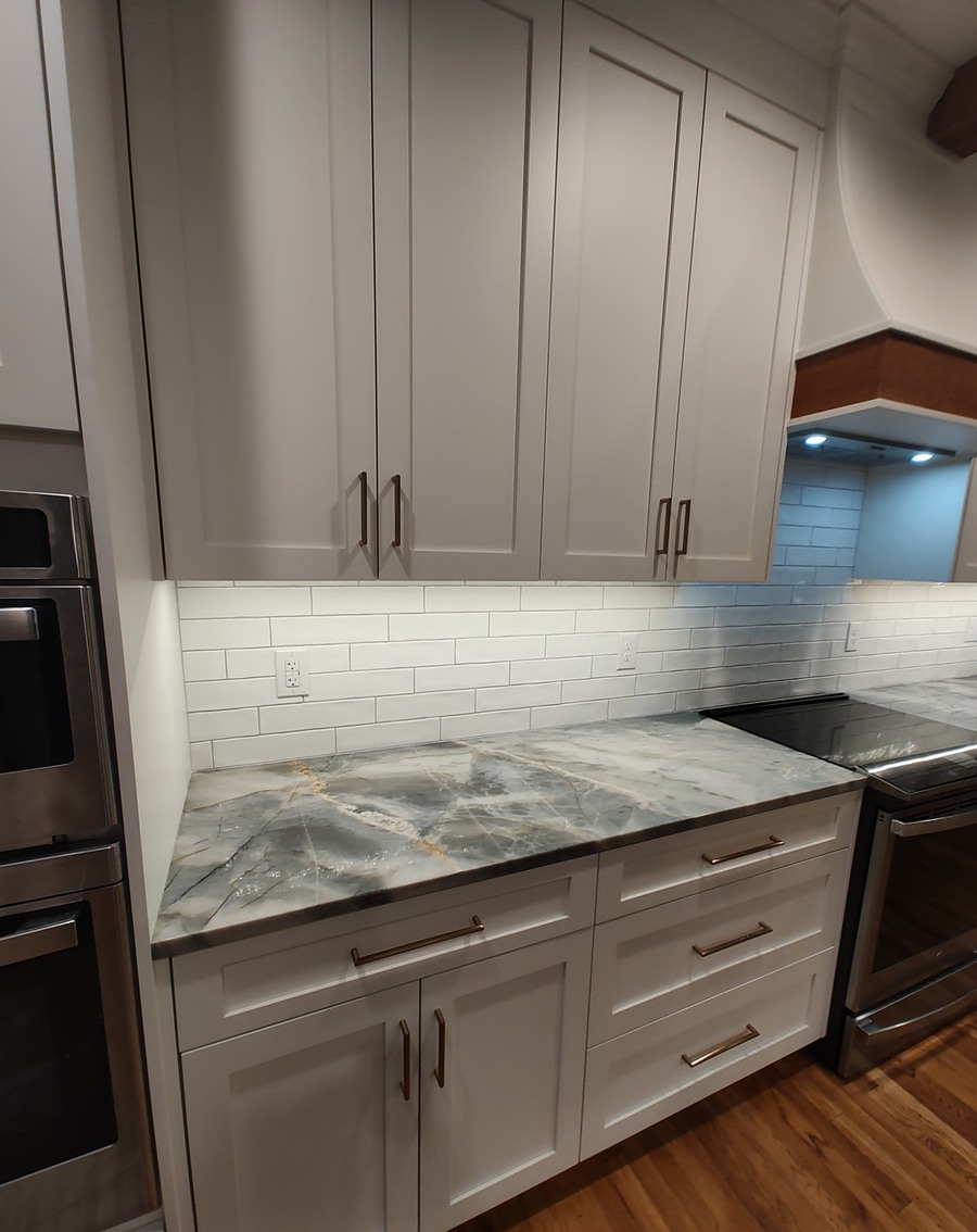 Full run of white kitchen cabinetry with marble-look counters and stainless appliances