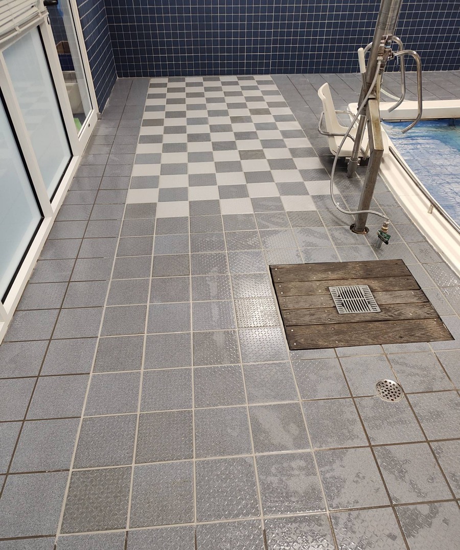 Grey and white checkerboard tile floor with a custom wood-inlay drain cover