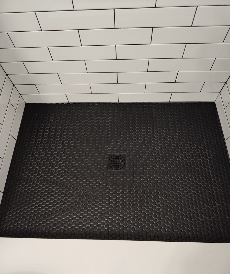 Black penny tile shower floor with a matte black drain